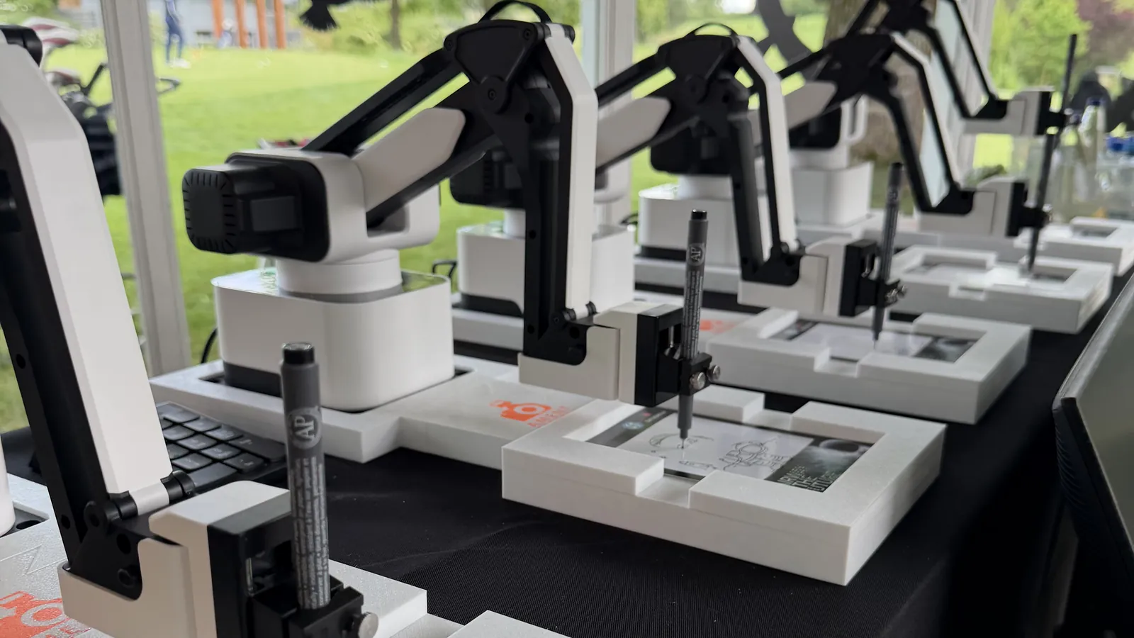 Fünf KI Zeichenroboter zeichnen Gäste-Porträts bei einem Firmenevent im Golfclub Stuttgart Solitude mit Blick auf den Golfplatz