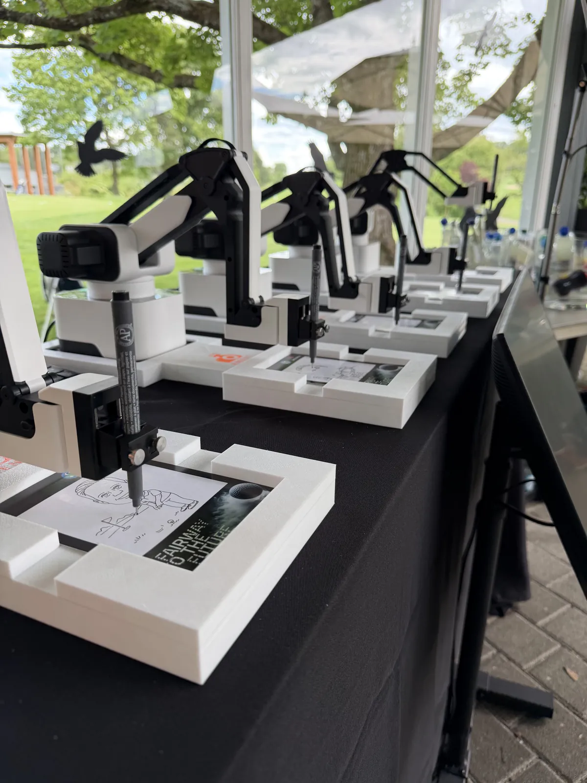 KI Zeichenroboter zeichnen Porträts in einem verglasten Pavillon mit Blick auf den Golfplatz des Golfclub Stuttgart Solitude