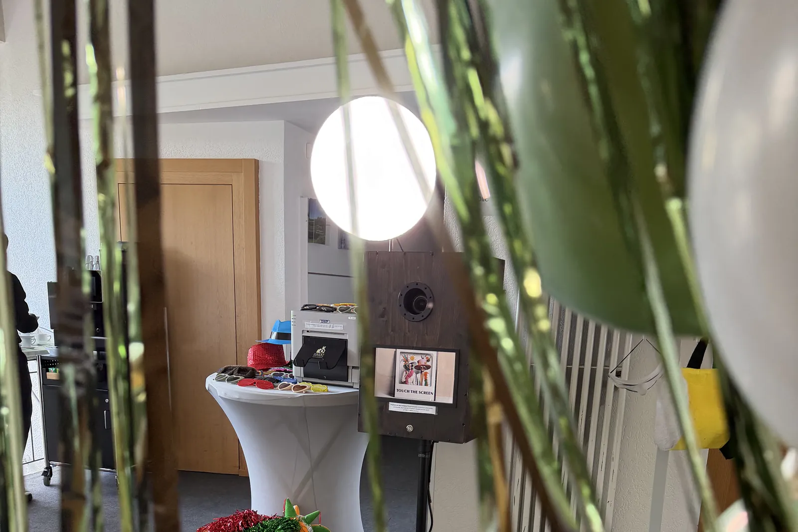 Klassische Holz-Fotobox mit Studiolicht hinter goldenem Lametta-Vorhang und Ballons bei einer Feier in der Marienburg Stuttgart